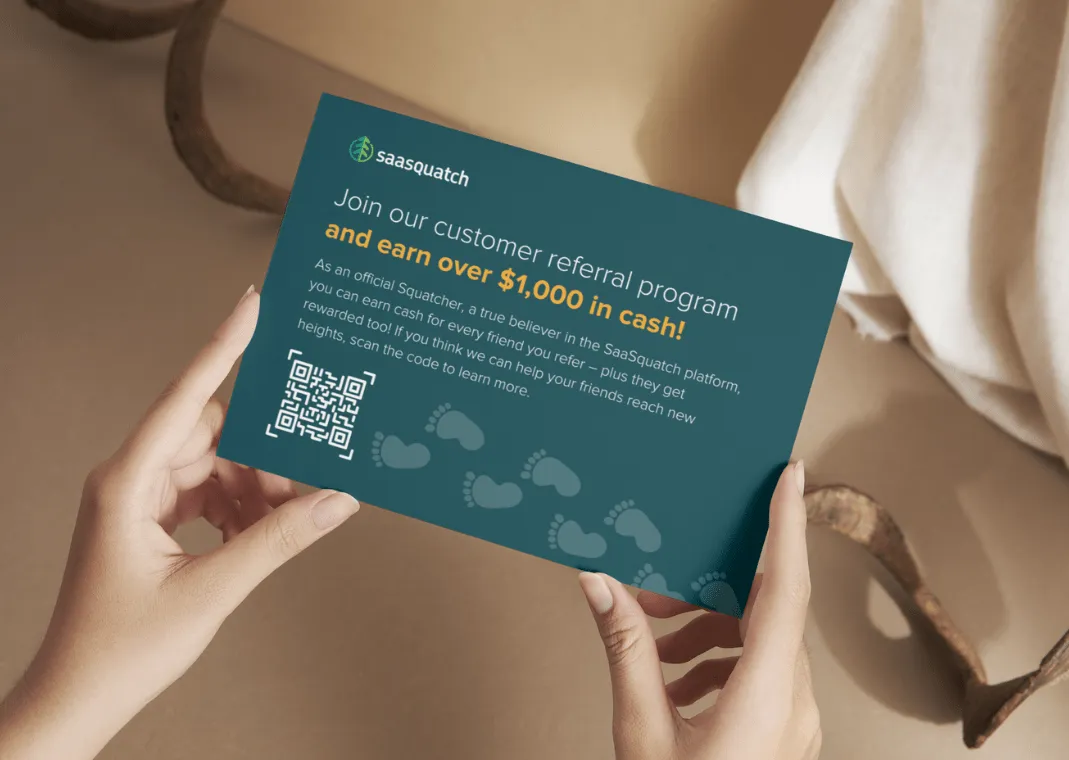 Woman holding a promotional postcard that is promoting a custoemr referral program for saasquatch